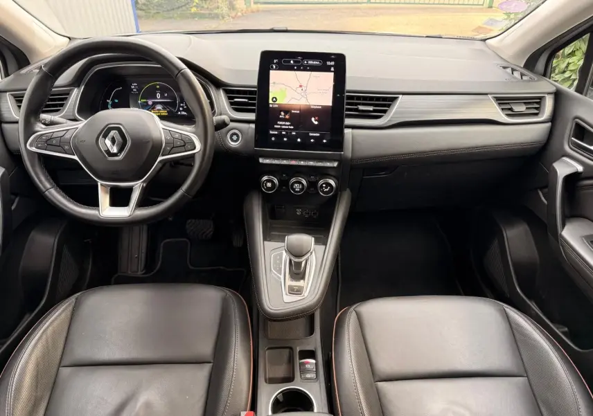 Intérieur du Renault Captur 1.6 E-TECH hybride 2021, vue frontale du tableau de bord avec écran tactile et sièges cuir noirs.