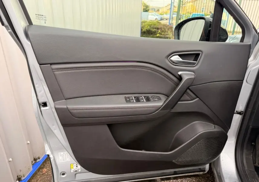 Porte intérieure côté gauche du Renault Captur gris Highland 2021, avec commandes de vitres et poignée intégrée.