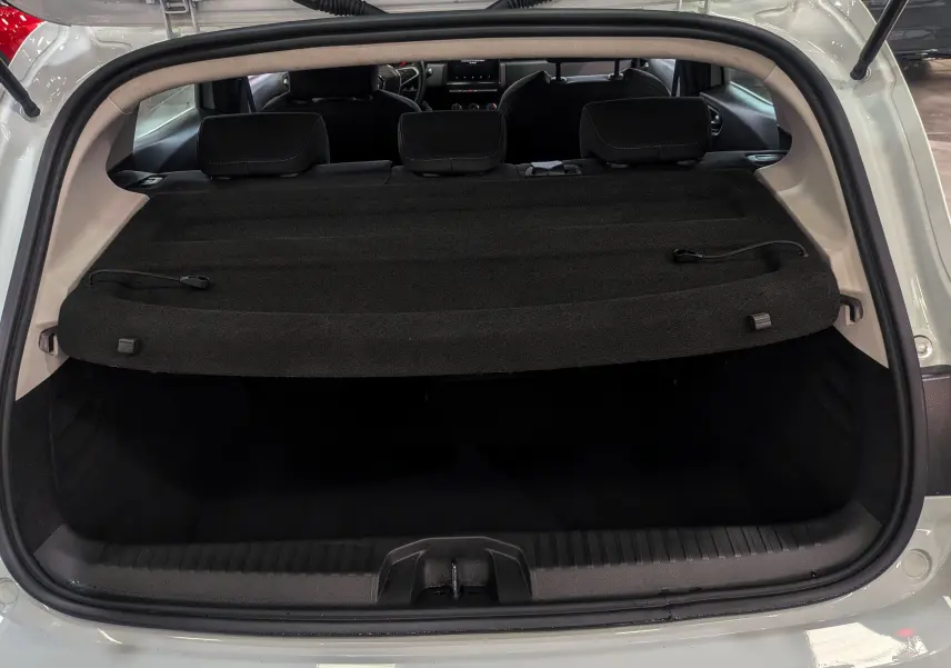 Coffre ouvert vu de l'arrière d'une Renault Clio V Blanc Glacier, avec cache-bagages et sièges arrière visibles.