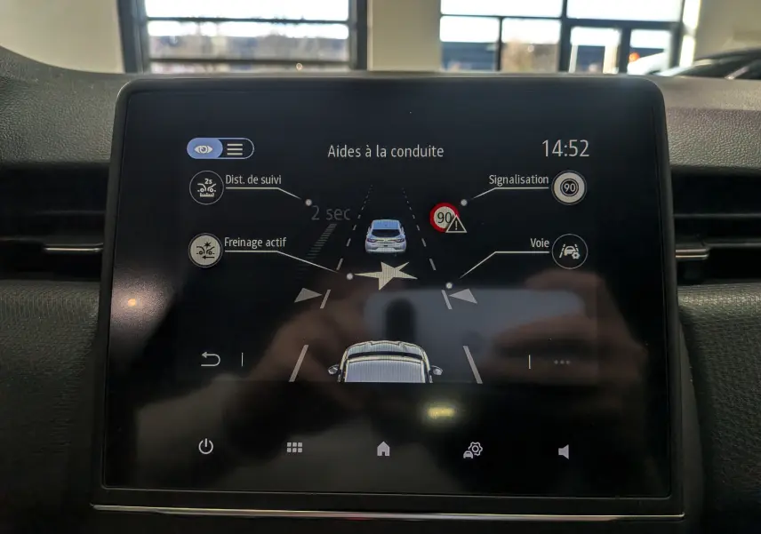 Écran tactile intérieur de la Renault Clio V blanc glacier montrant les aides à la conduite et alertes de sécurité.