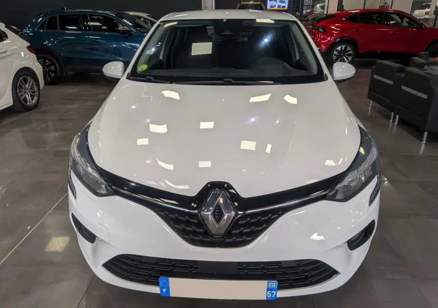 Vue avant d'une Renault Clio V Business blanche Glacier, avec calandre noire et logo Renault bien visible en concession.