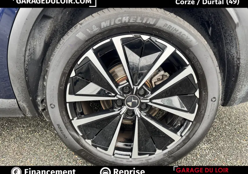 Gros plan sur la jante noire et argentée d’un DS7 Crossback bleu, avec pneu Michelin Primacy 4 visible.