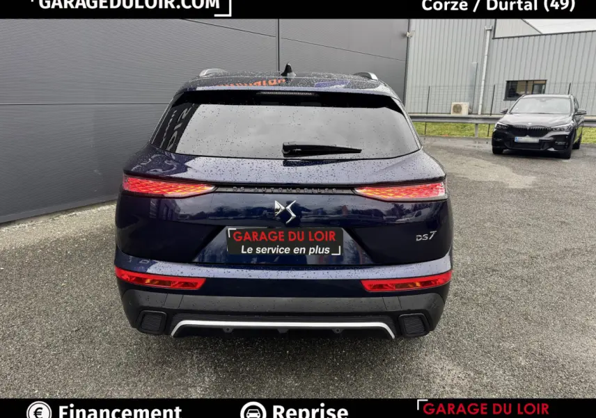 Vue arrière d'un DS7 Crossback bleu 2024 avec feux LED étirés et logo DS centré sur un parking.
