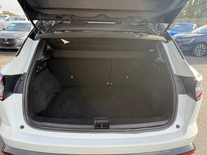 Coffre ouvert vu de l'arrière d'un Renault Austral blanc nacré avec toit noir étoilé, version hybride 2025.