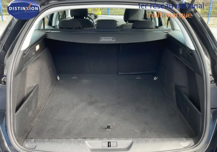 Coffre ouvert vu de l'arrière d'une Peugeot 308 SW noire, montrant un espace de chargement propre et spacieux.