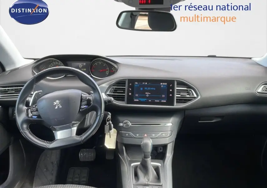 Vue intérieure frontale du tableau de bord noir de la Peugeot 308 SW 2019 avec volant cuir et écran tactile central allumé.