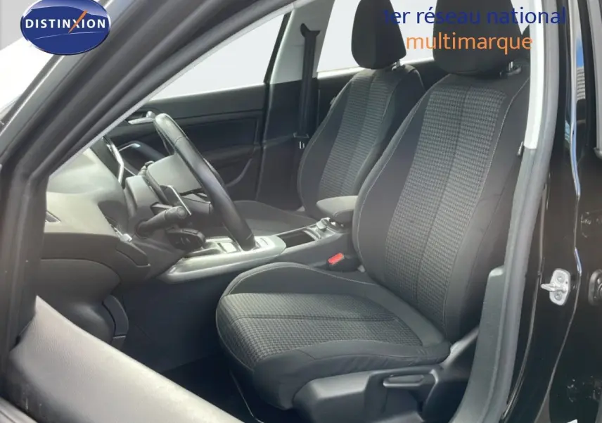 Intérieur de la Peugeot 308 SW 2019 en noir, vue côté conducteur montrant les sièges tissu et le volant cuir.