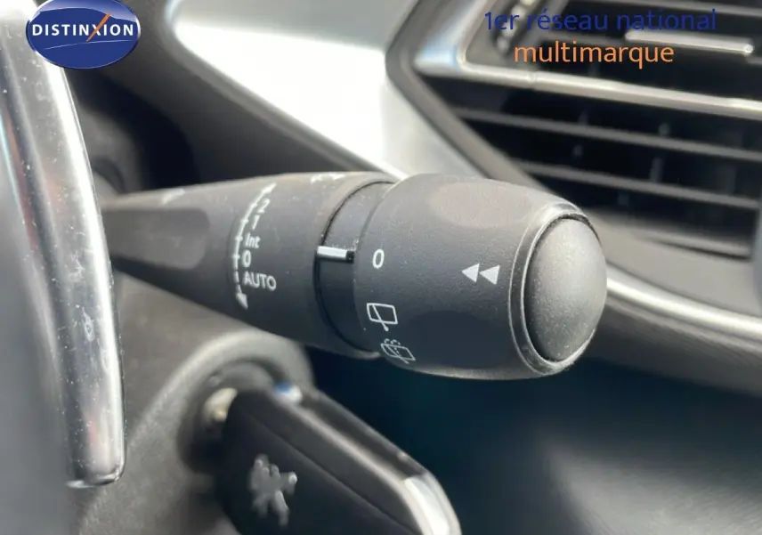 Gros plan sur la commande d’essuie-glace à gauche du volant dans l’habitacle noir d’une Peugeot 308 SW 2019.