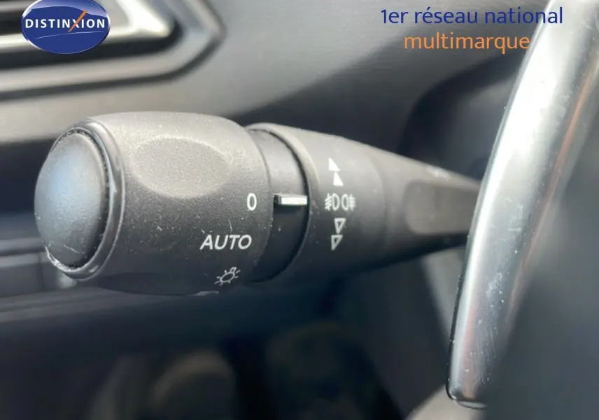 Gros plan sur la commande des phares avec réglage automatique dans l’habitacle d’une Peugeot 308 SW noire.