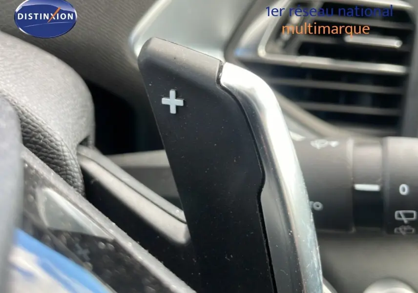 Gros plan sur la palette de changement de vitesse "+" côté droit du volant dans l'habitacle d'une Peugeot 308 SW noire.