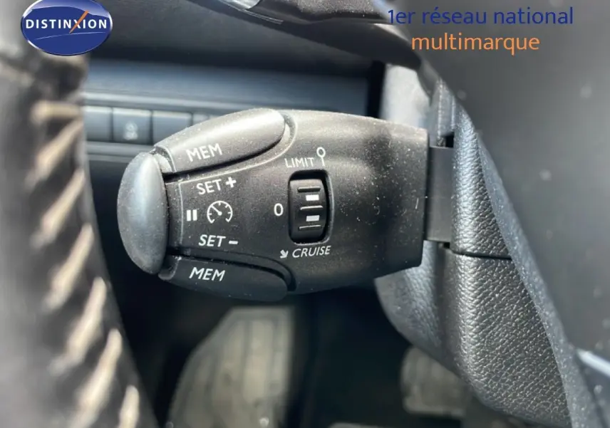 Gros plan sur la commande de régulateur de vitesse au volant d’un Peugeot 308 SW noir Perla Nera 2019.