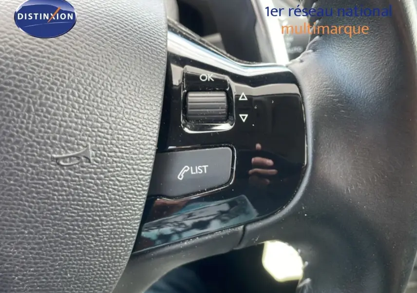 Gros plan sur les commandes au volant en cuir noir du Peugeot 308 SW 2019, avec boutons de gestion d’appels et menu.
