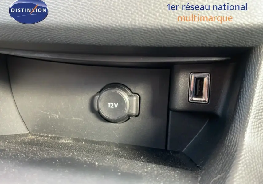 Prise 12V et port USB intégrés dans la console centrale d'une Peugeot 308 SW noire, vue intérieure rapprochée.