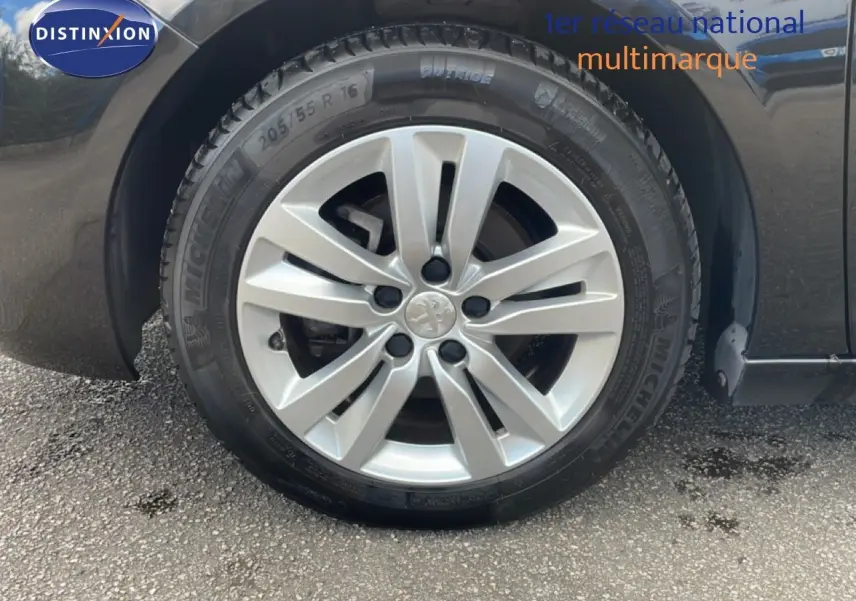 Gros plan sur la roue avant gauche d'une Peugeot 308 SW noire avec jante alliage argentée et pneu Michelin.