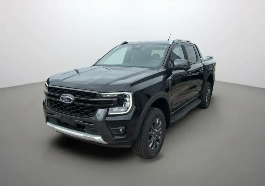Ford Ranger 3.0 V6 Wildtrak Plus noir agate vu en 3/4 avant droit, avec jantes alu et barres de toit visibles.