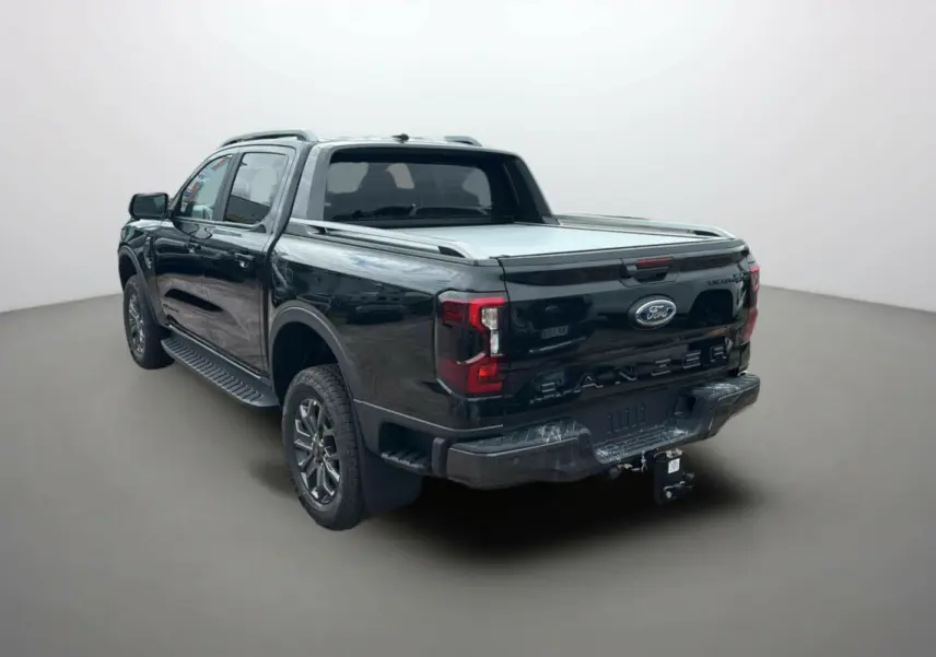 Vue 3/4 arrière droite du Ford Ranger noir agate avec benne couverte et attelage visible.