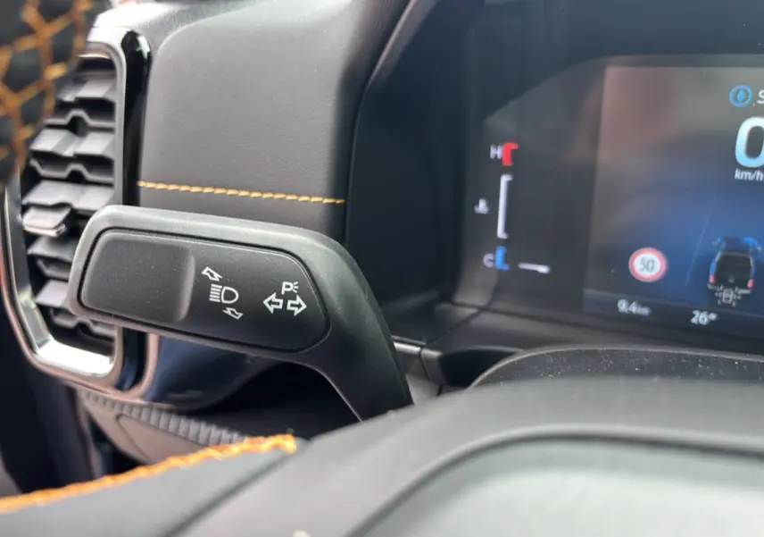 Gros plan sur la commande des clignotants et tableau de bord numérique du Ford Ranger Wildtrak Plus noir agate.