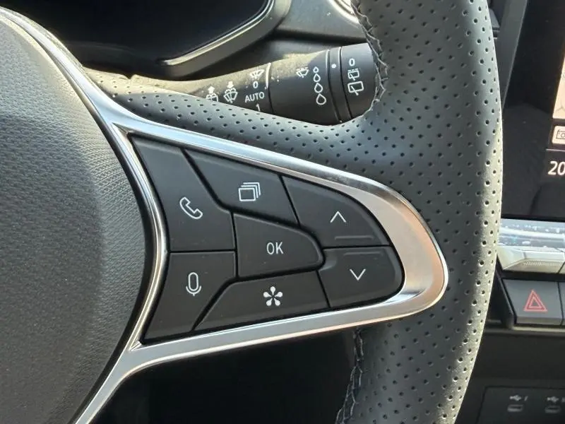 Gros plan sur les commandes multifonctions noires du volant perforé côté gauche du Renault Captur blanc nacré 2026.