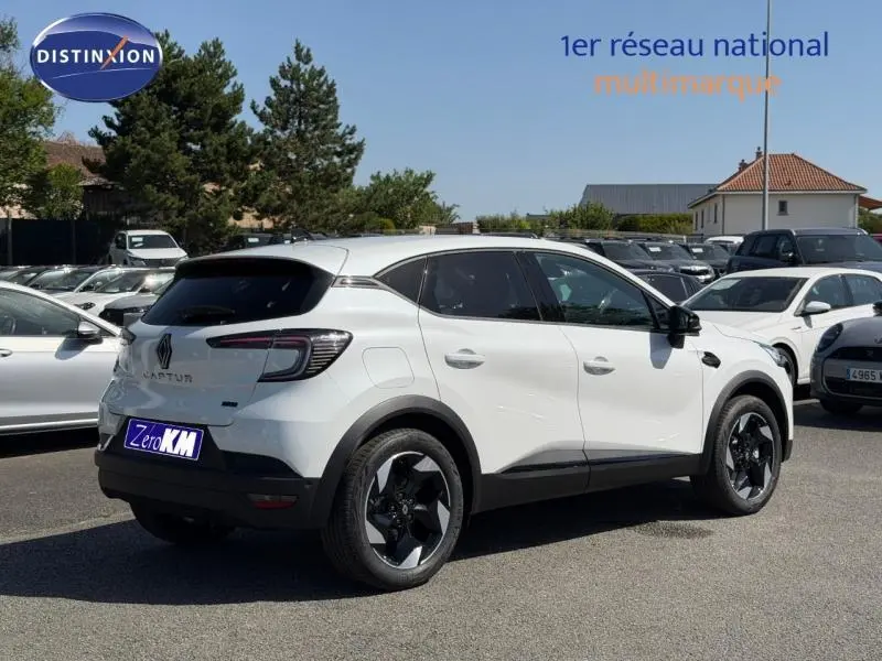 Renault Captur blanc nacré en vue 3/4 arrière droit, avec jantes alu noires et vitres arrière surteintées.