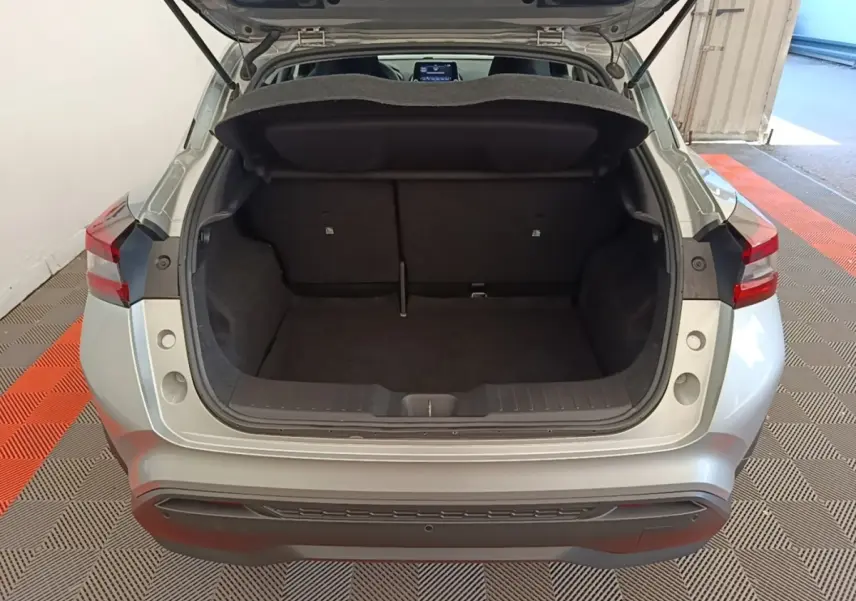 Vue arrière du coffre ouvert d'un Nissan Juke gris clair 2023, montrant l'espace de chargement intérieur.