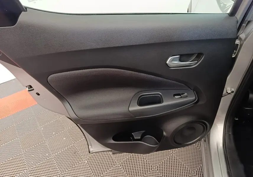 Vue rapprochée de la porte arrière droite gris clair du Nissan Juke 2023 avec poignée et haut-parleur intégrés.
