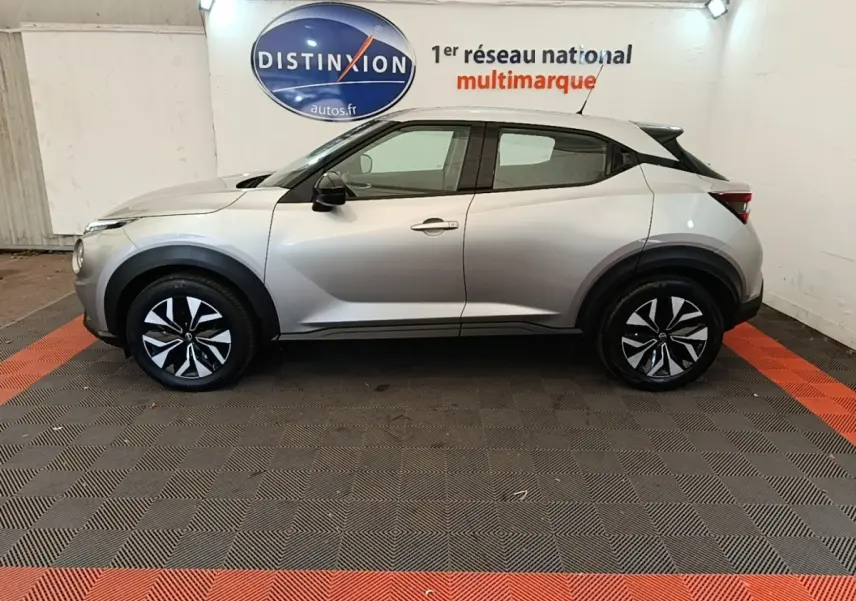 Vue latérale droite du Nissan Juke gris clair 2023 avec jantes bicolores et toit noir contrastant.