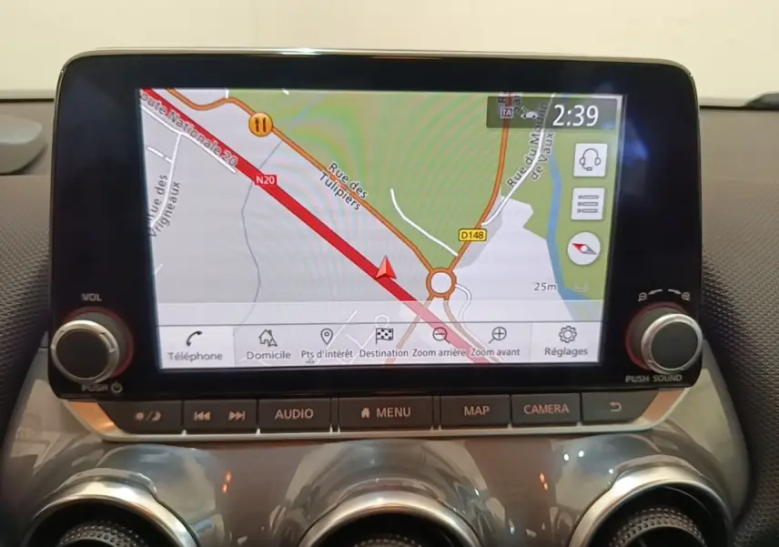 Écran tactile central du Nissan Juke 2023 affichant la navigation 3D avec commandes audio et climatisation en dessous.