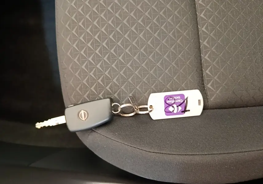 Clé Nissan posée sur un siège tissu gris foncé avec motif géométrique à l'intérieur du véhicule.