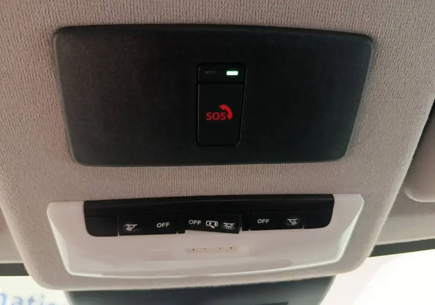 Gros plan sur le plafonnier intérieur avec bouton d'appel d'urgence SOS et commandes d'éclairage du Nissan Juke gris clair.
