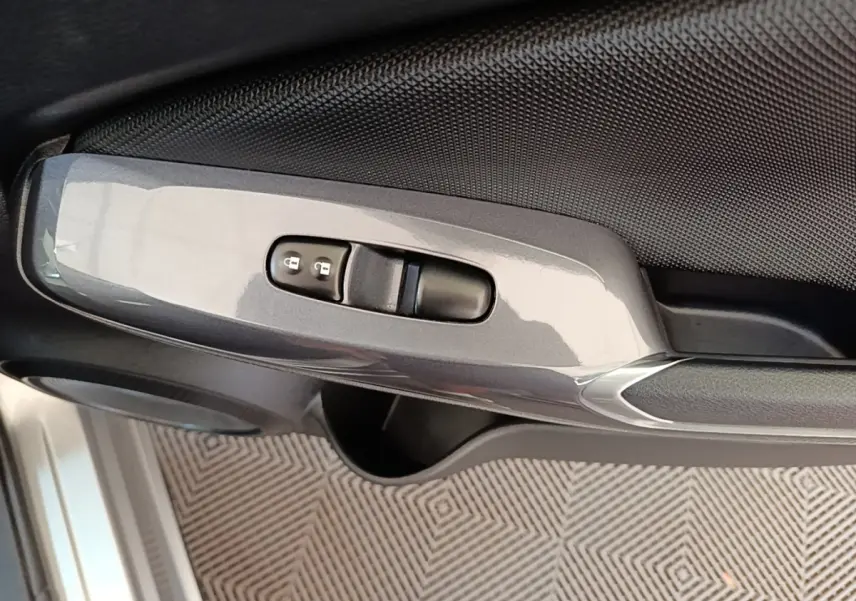 Détail de la commande de verrouillage centralisé sur la porte côté conducteur du Nissan Juke gris clair 2023.