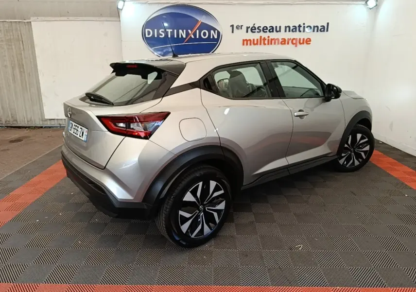 Nissan Juke gris clair en 3/4 arrière droit, avec toit noir et jantes alliage distinctives, stationné en intérieur.