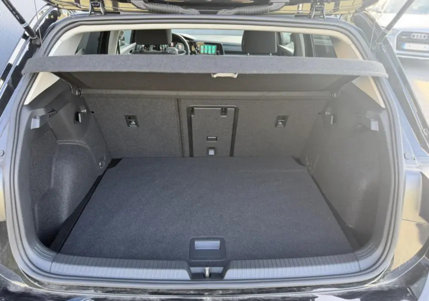 Coffre ouvert d'une Volkswagen Golf VIII noire, vue arrière montrant l'espace de chargement et la plage arrière.