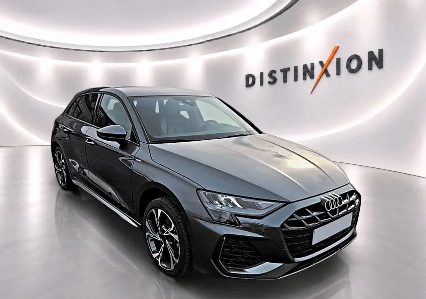 Audi A3 Sportback gris Daytona vue 3/4 avant droit dans un showroom lumineux avec logo Distinxion en arrière-plan.