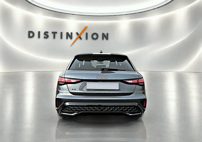 Vue arrière d'une Audi A3 Sportback gris Daytona avec feux LED et diffuseur arrière noir dans un showroom lumineux.