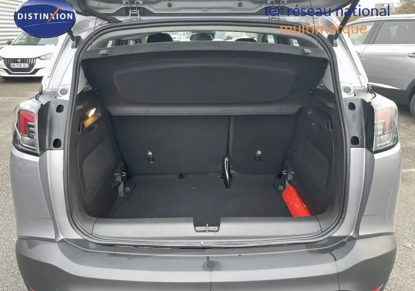 Coffre ouvert vu de l'arrière d'un Opel Crossland gris minéral métal, montrant l'espace de chargement vide.