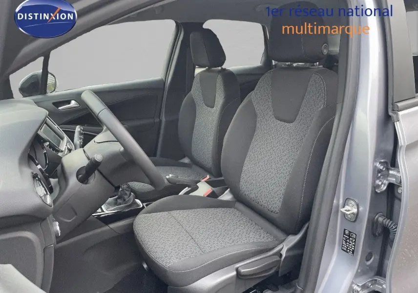 Vue intérieure côté conducteur de l'Opel Crossland gris minéral métal, montrant les sièges en tissu gris et la console centrale.