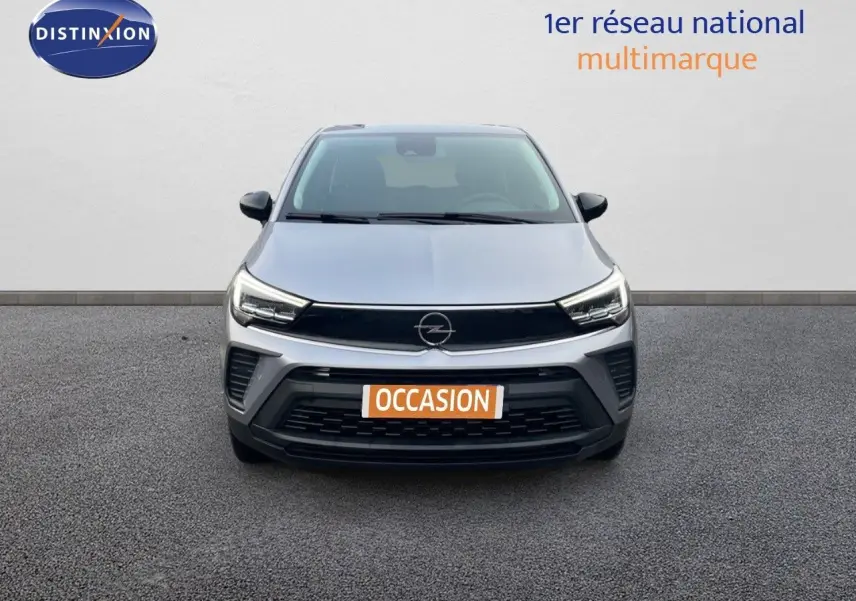 Vue frontale d'un Opel Crossland gris minéral métal avec calandre noire et phares LED allumés sur fond neutre.