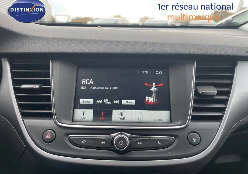 Vue rapprochée du tableau de bord de l'Opel Crossland gris minéral, avec écran tactile affichant la radio FM.