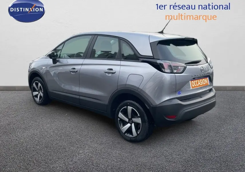Opel Crossland gris minéral métal vu en 3/4 arrière côté gauche, avec jantes alliage et toit noir contrasté.