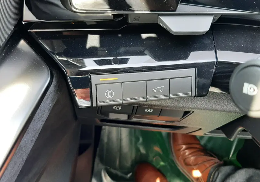 Gros plan sur les commandes noires du tableau de bord du Renault Espace gris, avec pédales et chaussure brune visibles au sol.