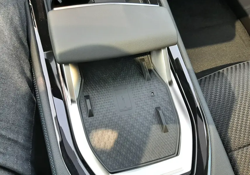 Gros plan sur la console centrale noire du Renault Espace VI avec surface de charge sans fil et accoudoir gris.