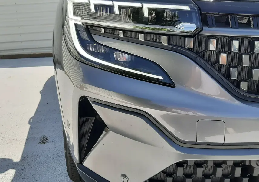 Gros plan sur le phare avant gauche du Renault Espace VI gris schiste métal, soulignant la calandre et les détails LED.