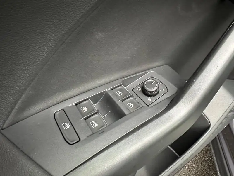 Gros plan sur les commandes de vitres et rétroviseurs côté gauche intérieur du Volkswagen T-Cross Gris Ascot 2025.