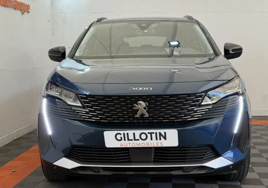 Vue frontale d'un Peugeot 3008 bleu avec calandre noire et feux LED en forme de griffes allumés.