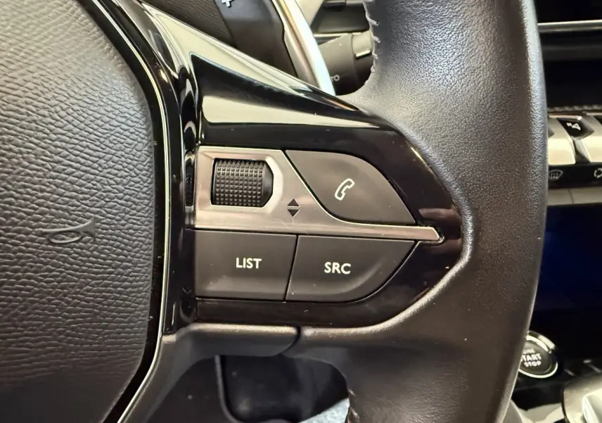 Gros plan sur les commandes gauche du volant cuir noir du Peugeot 3008 bleu, avec boutons LIST, SRC et téléphone.