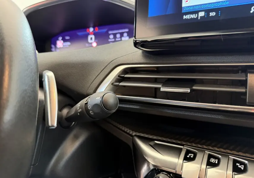 Gros plan sur le tableau de bord noir du Peugeot 3008 bleu, avec écran tactile et commandes de climatisation visibles.