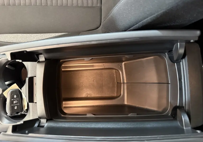 Vue plongeante sur la console centrale ouverte d’un Peugeot 3008 bleu, avec clé de voiture visible dans porte-gobelet.