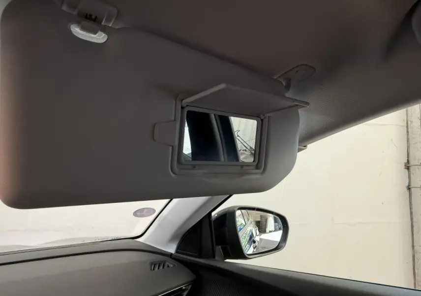 Détail intérieur du pare-soleil côté conducteur avec miroir, rétroviseur extérieur droit et tableau de bord noir du Peugeot 3008 bleu.
