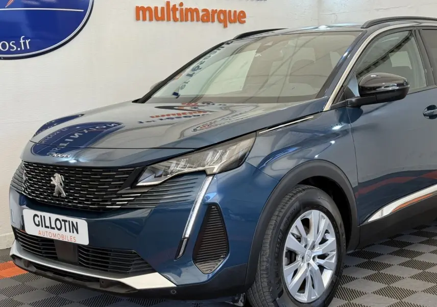 Vue 3/4 avant droit d'un Peugeot 3008 bleu avec calandre noire et feux LED distinctifs, stationné en intérieur.