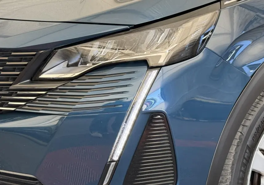 Gros plan sur le phare avant droit bleu du Peugeot 3008 2021 avec signature lumineuse en forme de griffes LED.